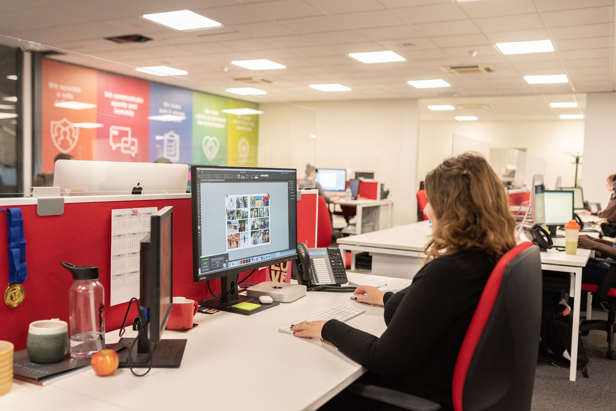 Designer laying out a personalised funeral order of service on screen in an open plan studio
